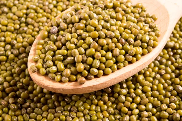 Mung beans in a wooden spoon on mung beans background