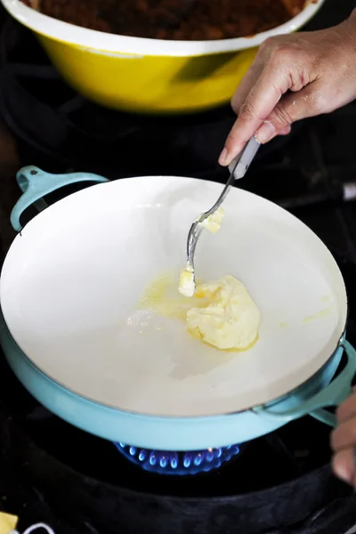 Hand holding fork putting butter to the pan