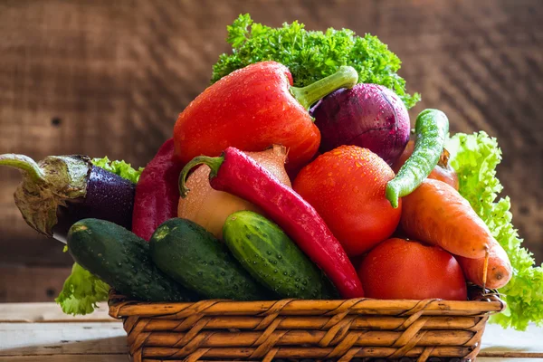 Fresh vegetables in basket on  wooden background