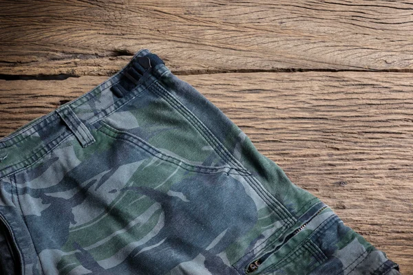 Camouflage pattern pants on wooden background