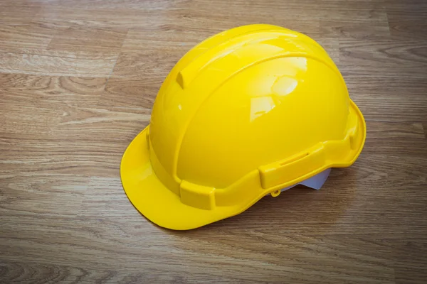 Yellow industrial protective helmet on wooden background