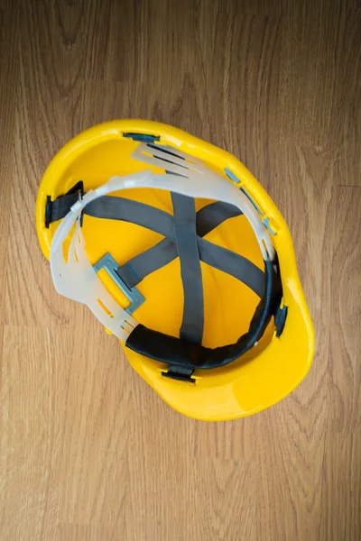 Yellow industrial protective helmet on wooden background