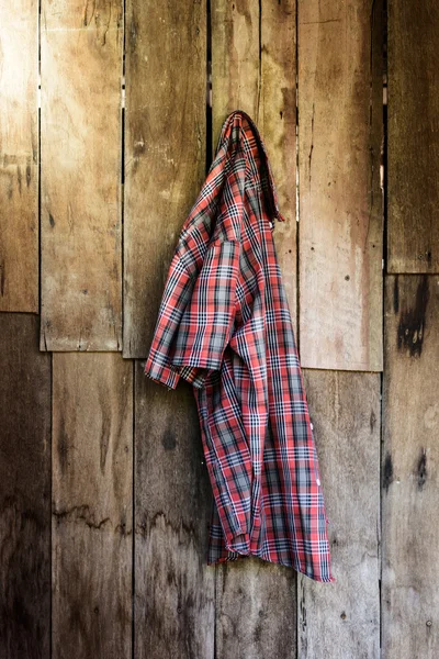 The old wrinkled plaid shirt hanging on wooden background
