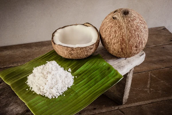 Coconuts and coconut flakes on banana leaf and coconut grater