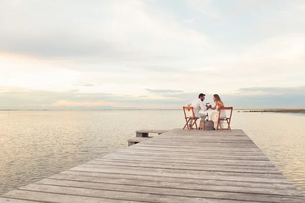 Couple drinking red wine at the seaside on a jetty