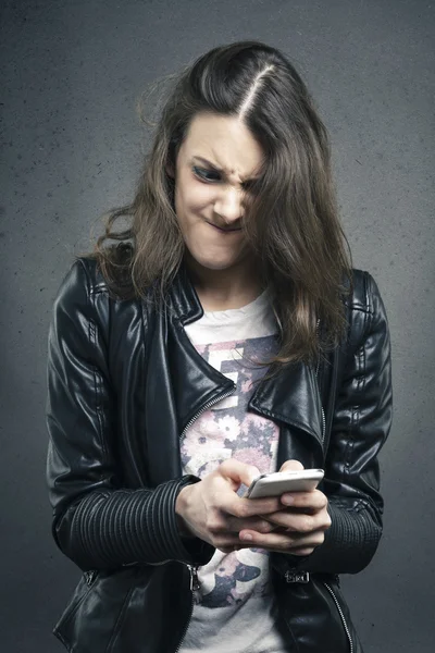 Angry young girl looking at phone with disgusting emotion