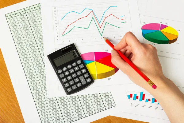 Womans hand draws  graph on the background of an office desk