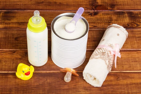 Baby milk formula feeding bottle, pacifier  on  dark wood.