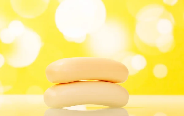 Two bar of soap in  bathroom on abstract yellow background.