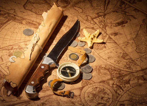 Compass, knife, coin and  starfish on  background  old maps.