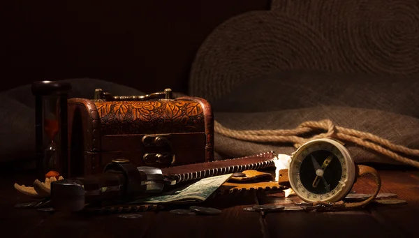 Old compass, treasure chest, hourglass, knife, money on  dark background.