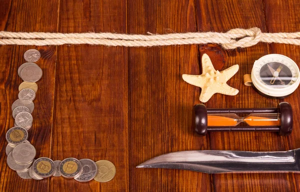 Old compass, money,  knife,  hourglass,  rope, starfish on   dark wood.