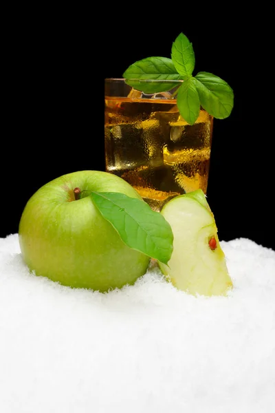 Frosty apple juice,ice cubes and apple with leaves on black on snow