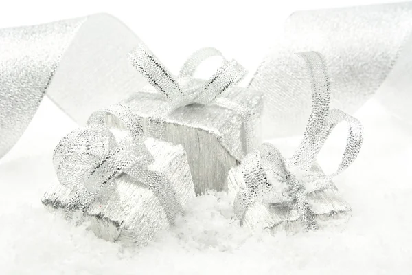 Three silver christmas gifts with silver ribbon on snow
