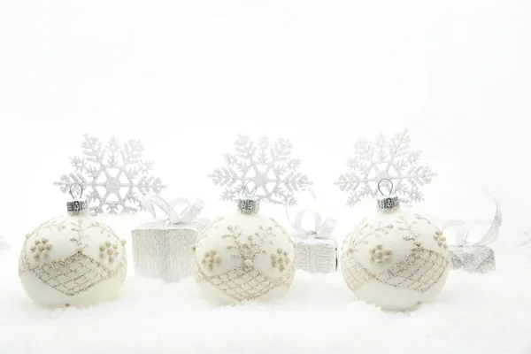 Silver christmas gifts and baubles with snowflakes on snow