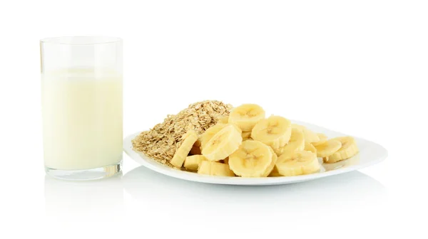 Macro shot slices banana on plate with glass of milk on white