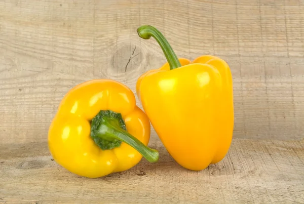 Studio shot of yellow bell peppers on wooden plank