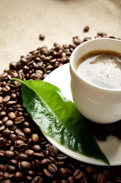 Macro cropped shot of frothy coffee with green leaf on linen cloth