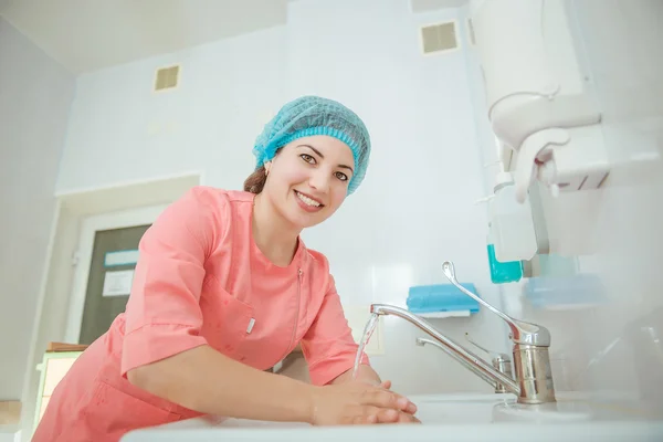 Young beautiful nurse washes hands