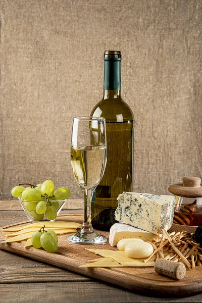 Various types of cheese, grapes, honey,  bottle of wine