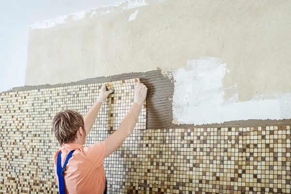 Laying Ceramic Tiles. Tiler placing ceramic wall tile in position over adhesive