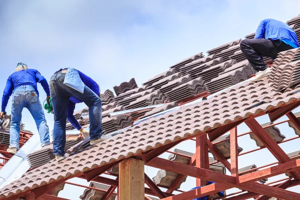 Workers install roof tile for house
