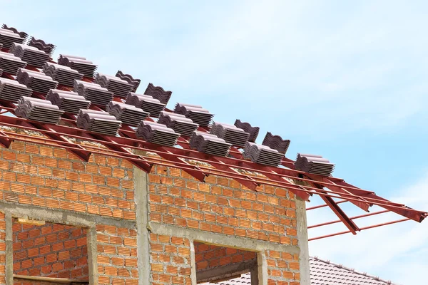 Roof under construction with stacks of roof tiles for home build