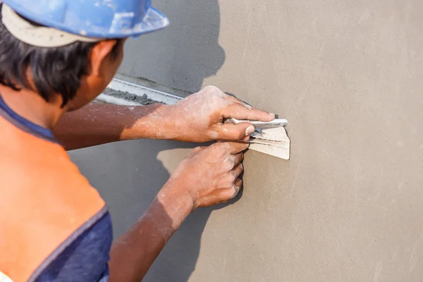 Plasterer concrete worker at wall of house construction