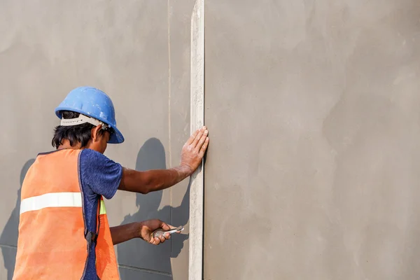 Plasterer concrete worker at wall of house construction