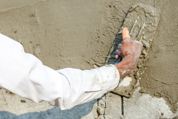 Plasterer concrete worker at wall of house construction