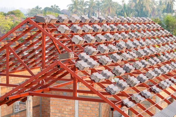 Roof under construction with stacks of roof tiles for home build