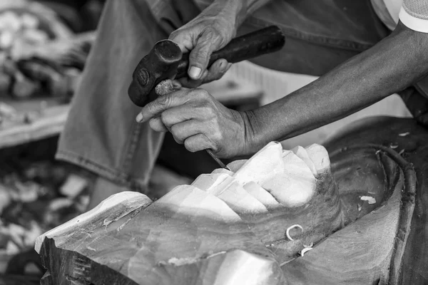 Hand of carver carving wood in black and white color tone