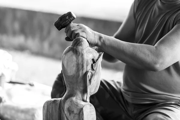 Hand of carver carving wood in black and white color tone