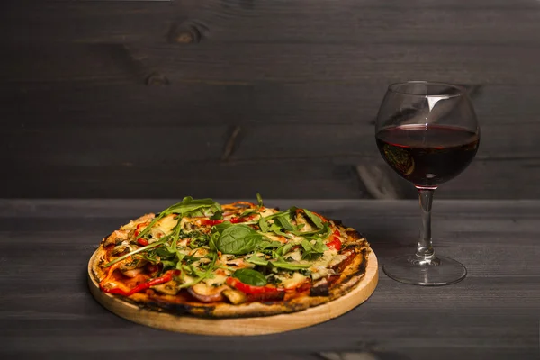 Pizza and a glass of red wine on wooden background
