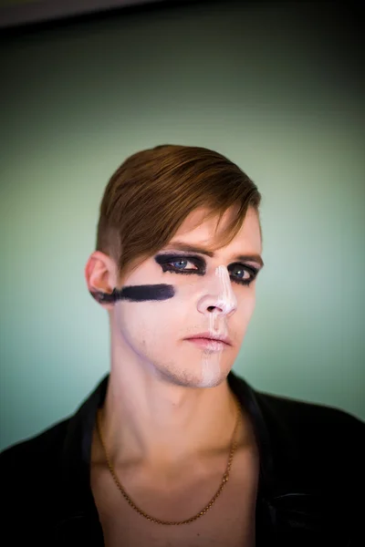 Composite image of serious young german fan with face paint against large football stadium