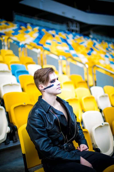 Relaxed fashion for men in leather jacket posing while sitting in the stadium