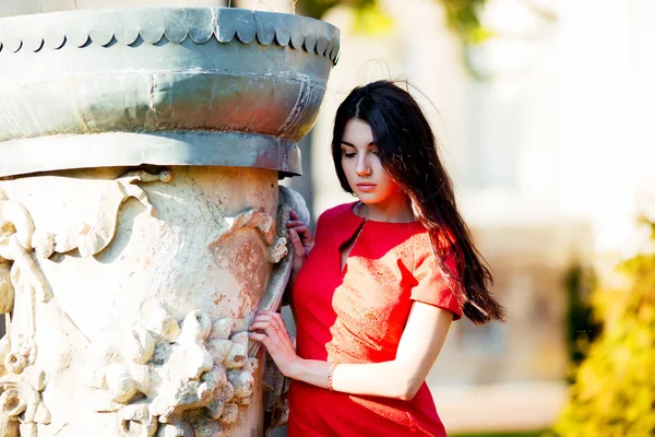 Young pretty beautiful woman walking in the old town and looking to the side. Stylish girl in a red blouse poses outdoors