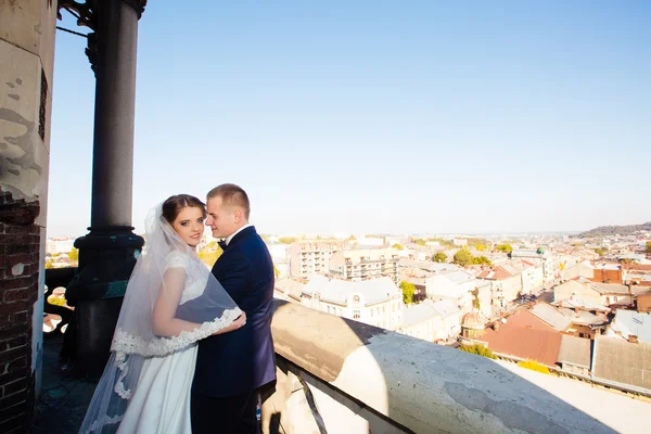 Happy gorgeous bride and stylish groom with true emotions on the roof on background cityscape, bride closeup