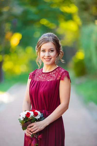 The portrait of spring girl in green trees,flowers,garden,park.Long-haired,light-haired,blonde girl,woman with bouquet of green flowers in hands.Springtime.Beautiful,awesome girl.Girl with sunny spica