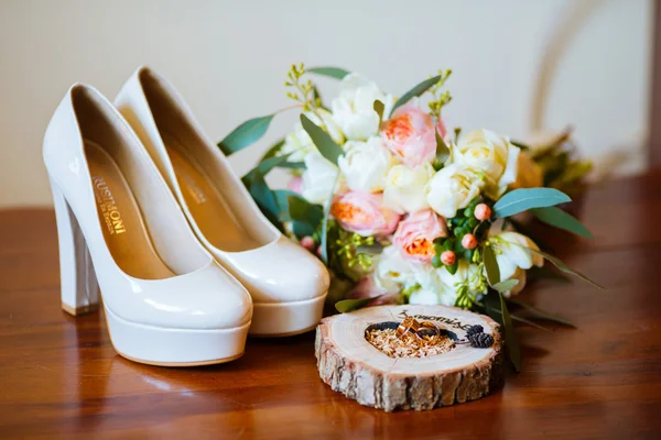 Bouquet of flowers and wedding rings lie on bare wooden heart-shaped