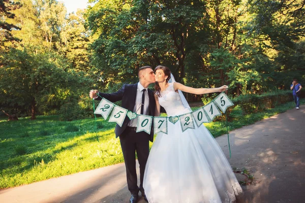 Beautiful wedding couple. The bride and groom in wedding day walking outdoors in spring nature. Bridal couple Newlywed happy woman and man embracing a green park.