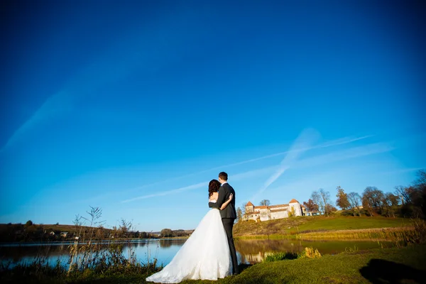 Happy bride and handsome brunette beautiful bride in a white dress, embrace under the arc