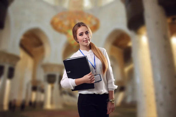 Young beautiful girl standing in a museum with a folder in hands