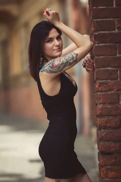 Beautiful girl in a black dress stands near architectural struct