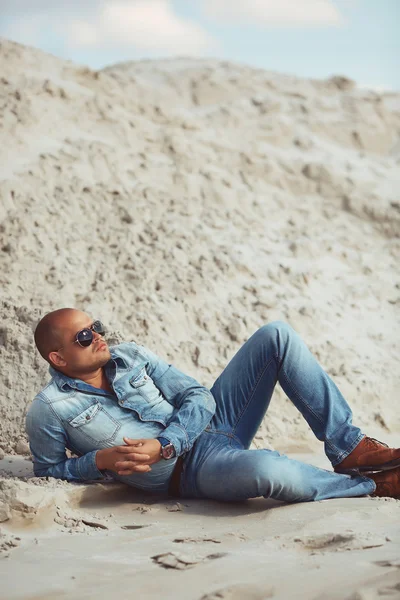 Fashionable stylish man lying on the sand