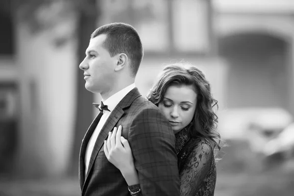 Black and white photo of beautiful bride embracing groom from ba