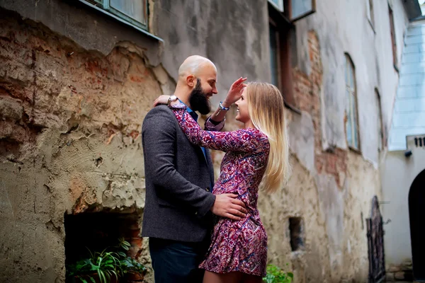 One beautiful stylish couple of young woman and senior man with long black beard sitting embracing close to each other outdoor in autumn street on stairs sunny day, horizontal picture