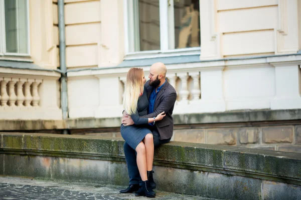 Happy couple in love with each other,One beautiful stylish couple of young woman and senior man with long black beard   embracing close to each other outdoor in autumn street on stairs sunny day