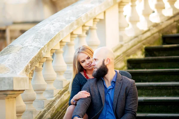 Happy couple in love with each other,One beautiful stylish couple of young woman and senior man with long black beard   embracing close to each other outdoor in autumn street on stairs sunny day
