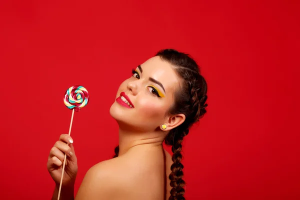 Happy young woman with lollipop, against a background of red background